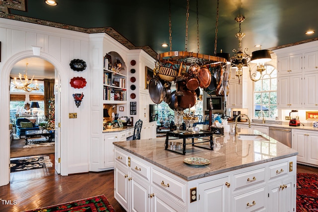 kitchen with white cabinets, light stone countertops, dark wood-type flooring, and a kitchen island with sink