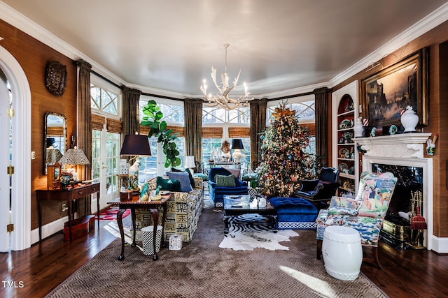 living room with a high end fireplace, a notable chandelier, ornamental molding, and dark wood-type flooring