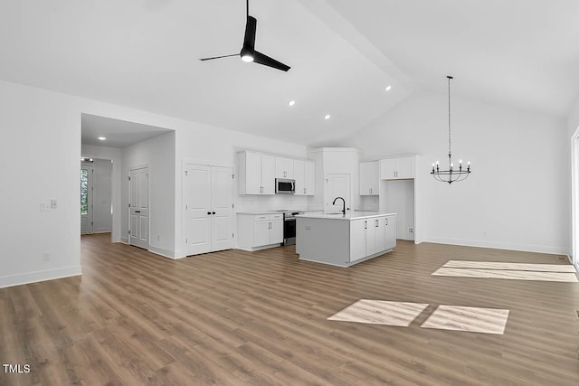 kitchen featuring white cabinets, an island with sink, appliances with stainless steel finishes, light wood-type flooring, and vaulted ceiling