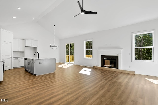 unfurnished living room with ceiling fan with notable chandelier, light hardwood / wood-style flooring, and plenty of natural light