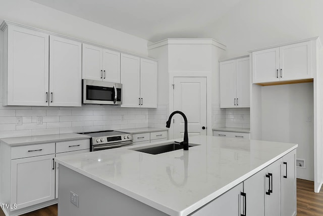 kitchen with a kitchen island with sink, sink, light stone counters, appliances with stainless steel finishes, and white cabinetry