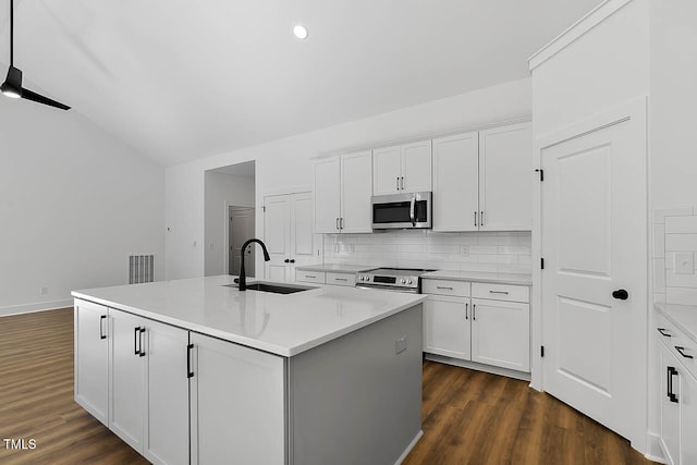 kitchen featuring stainless steel appliances, white cabinets, dark wood-type flooring, sink, and a center island with sink