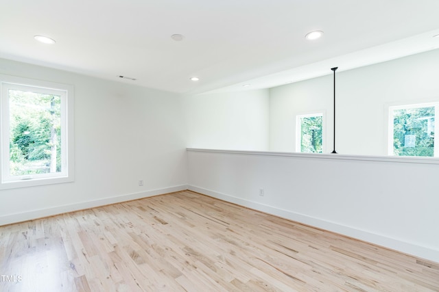 empty room with plenty of natural light and light hardwood / wood-style flooring