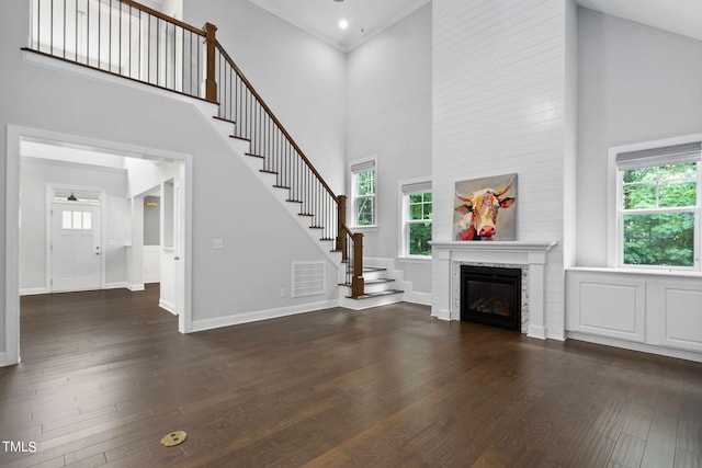 unfurnished living room with a towering ceiling, crown molding, and dark hardwood / wood-style floors