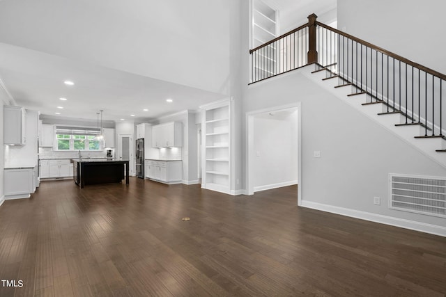 unfurnished living room with sink, dark hardwood / wood-style flooring, and built in features