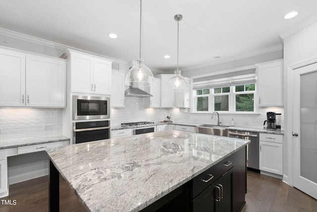 kitchen featuring stainless steel appliances, white cabinetry, a center island, and decorative light fixtures