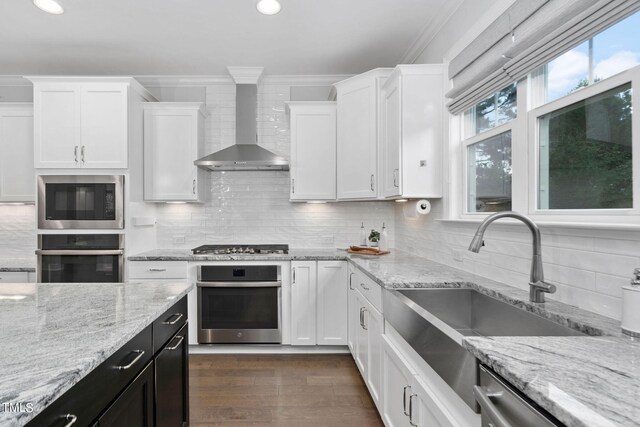 kitchen featuring stainless steel appliances, sink, white cabinetry, wall chimney exhaust hood, and tasteful backsplash