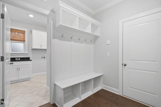 mudroom with ornamental molding, sink, and light tile patterned floors