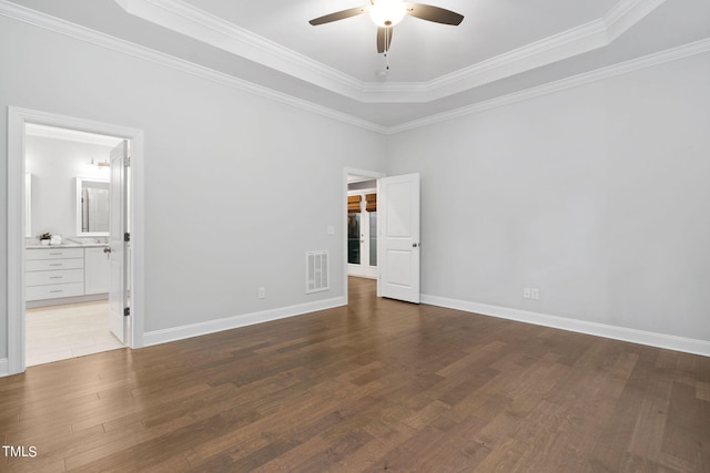 empty room featuring light hardwood / wood-style floors, ornamental molding, and a tray ceiling