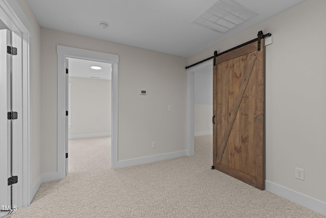 unfurnished bedroom featuring light colored carpet and a barn door