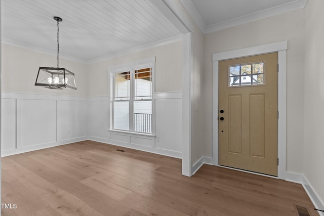 foyer featuring light wood-type flooring, a wealth of natural light, a chandelier, and ornamental molding