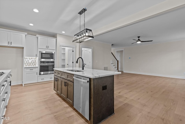 kitchen featuring sink, white cabinetry, a kitchen island with sink, light stone countertops, and appliances with stainless steel finishes