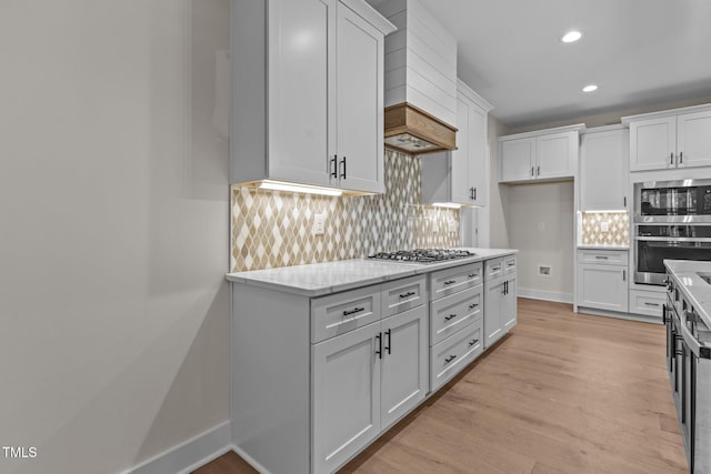 kitchen featuring light stone counters, decorative backsplash, white cabinets, and stainless steel appliances