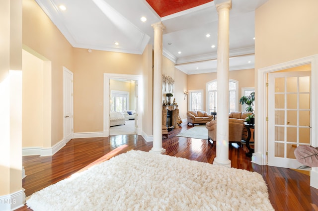 entrance foyer featuring crown molding, dark hardwood / wood-style floors, and decorative columns