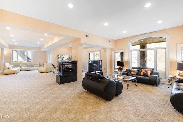 living room with light carpet, a fireplace, and a healthy amount of sunlight