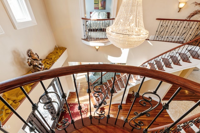 staircase with hardwood / wood-style flooring and a chandelier