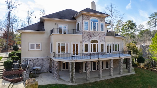 rear view of property featuring a patio area, a yard, central AC unit, and a balcony