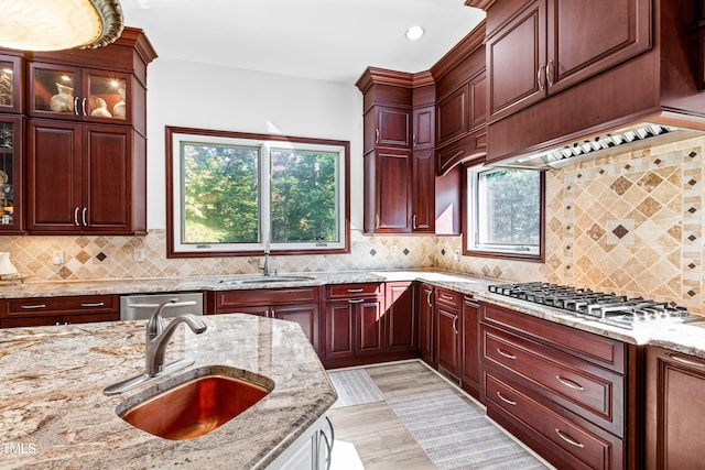 kitchen featuring sink, light stone counters, a healthy amount of sunlight, and tasteful backsplash