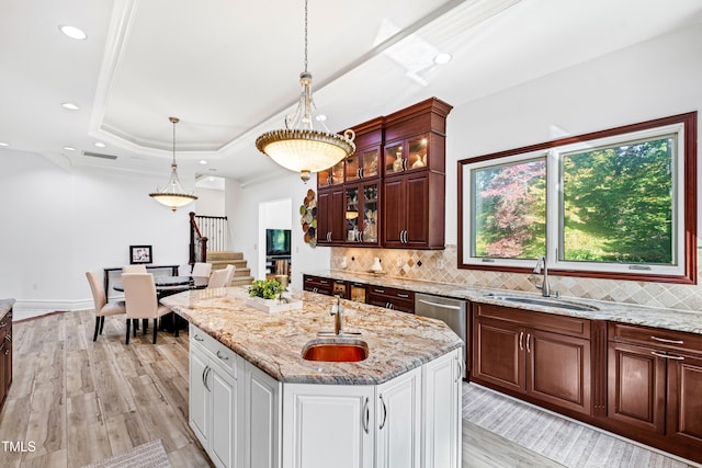 kitchen featuring white cabinetry, a kitchen island with sink, sink, and light wood-type flooring