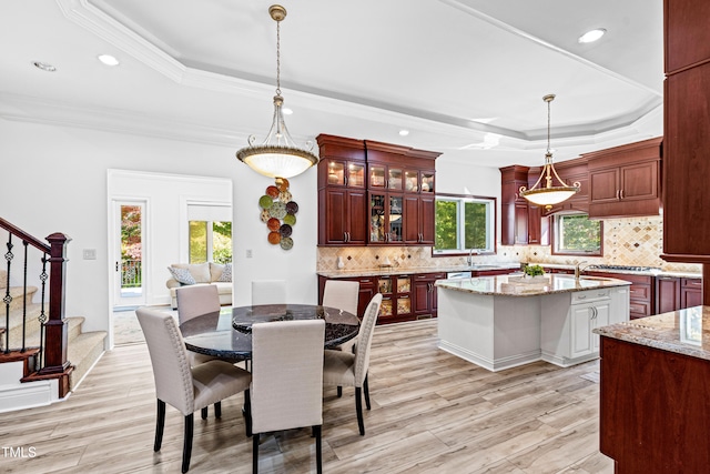 dining space with light hardwood / wood-style flooring, a raised ceiling, and a wealth of natural light