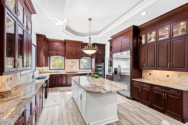 kitchen featuring a kitchen island, hanging light fixtures, stainless steel appliances, decorative backsplash, and light hardwood / wood-style flooring