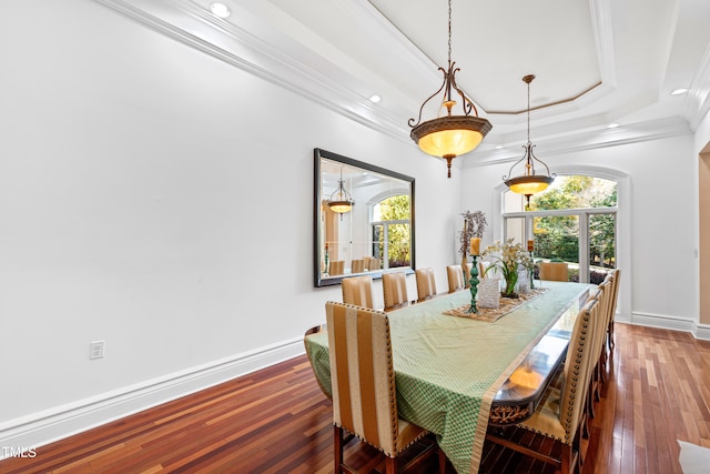 dining room with a tray ceiling, dark wood-type flooring, crown molding, and a healthy amount of sunlight