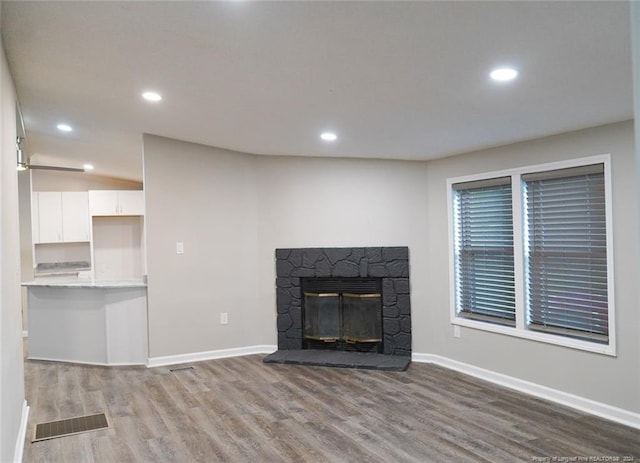 unfurnished living room with a stone fireplace and wood-type flooring