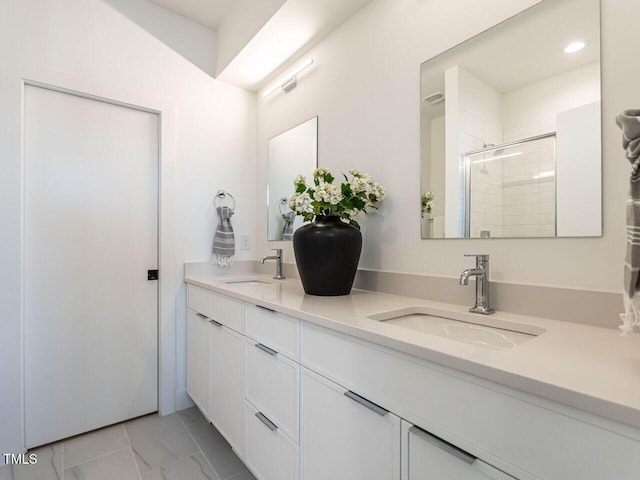 bathroom with a sink, a stall shower, and double vanity