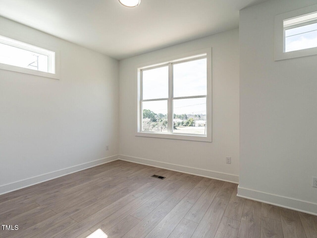 unfurnished room with wood finished floors, a healthy amount of sunlight, and baseboards