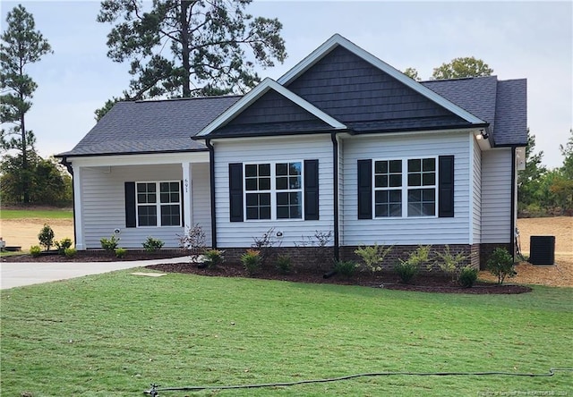 view of front facade featuring central air condition unit, roof with shingles, and a front lawn