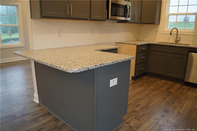 kitchen featuring dark wood finished floors, decorative backsplash, appliances with stainless steel finishes, and a sink