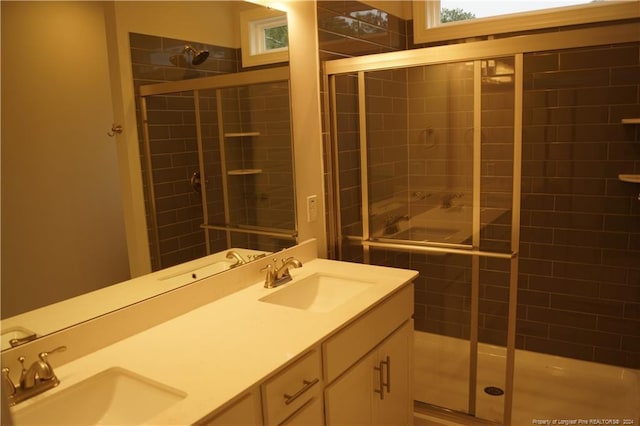 full bathroom featuring double vanity, a tile shower, and a sink