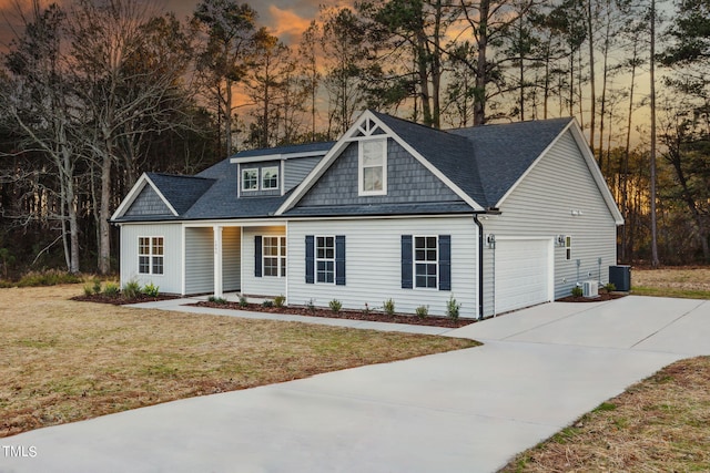 view of front of house with a yard, central AC, and a garage