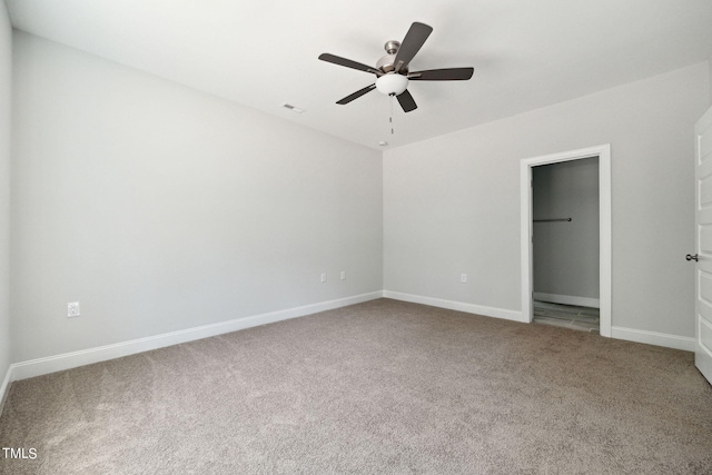 unfurnished bedroom featuring a closet, ceiling fan, carpet, and a walk in closet