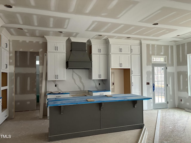 kitchen with a kitchen bar, custom range hood, and white cabinets