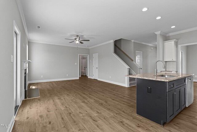 kitchen with ceiling fan, light wood-type flooring, white cabinets, and an island with sink