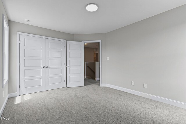 unfurnished bedroom featuring light colored carpet and a closet