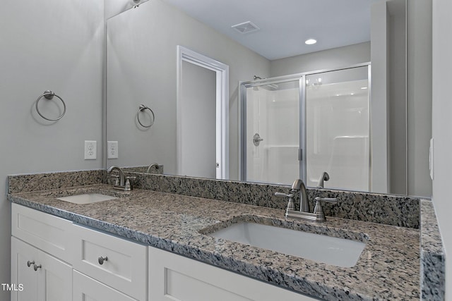 bathroom featuring a shower with door and dual vanity