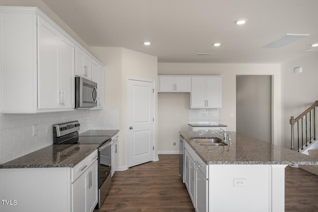 kitchen with an island with sink, stainless steel appliances, sink, white cabinetry, and dark hardwood / wood-style flooring