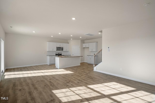 unfurnished living room featuring sink and light hardwood / wood-style floors