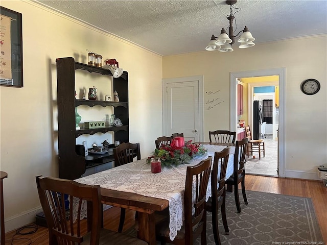 dining room featuring dark hardwood / wood-style flooring, ornamental molding, a chandelier, and a textured ceiling