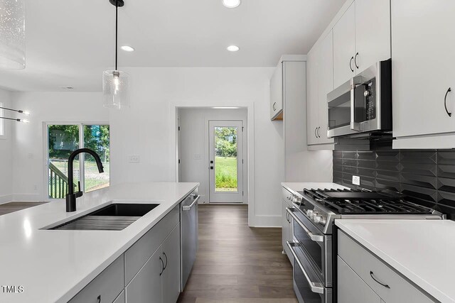 kitchen with hanging light fixtures, a healthy amount of sunlight, stainless steel appliances, and white cabinets