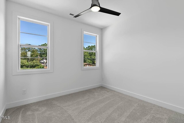 spare room with ceiling fan, light colored carpet, and plenty of natural light