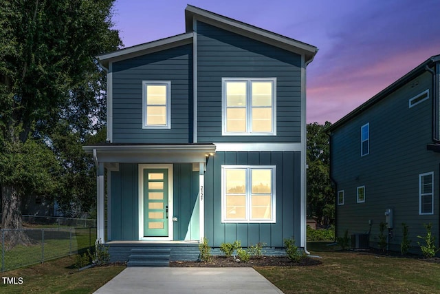 contemporary house featuring board and batten siding, central AC, a front lawn, and fence