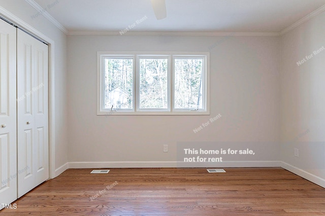 unfurnished bedroom featuring a closet, crown molding, wood-type flooring, and ceiling fan