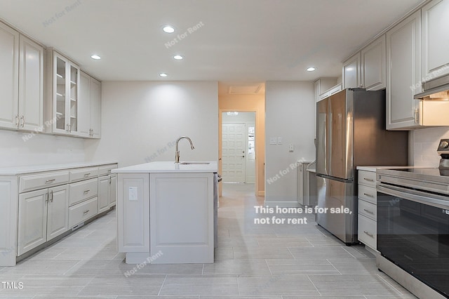 kitchen featuring white cabinetry, light tile flooring, sink, an island with sink, and stainless steel appliances