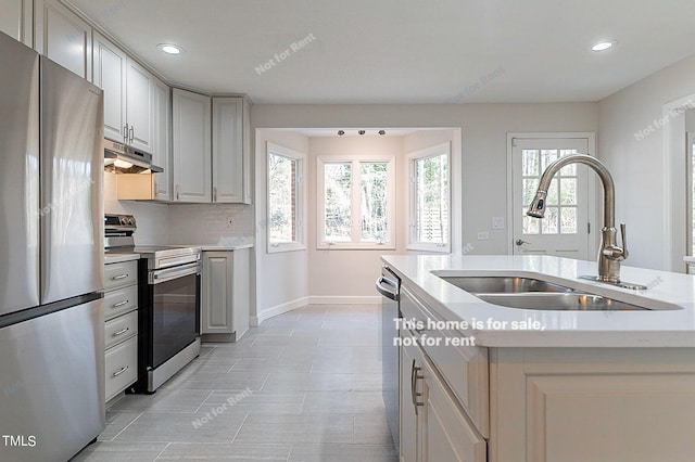 kitchen featuring appliances with stainless steel finishes, sink, a wealth of natural light, and light tile floors