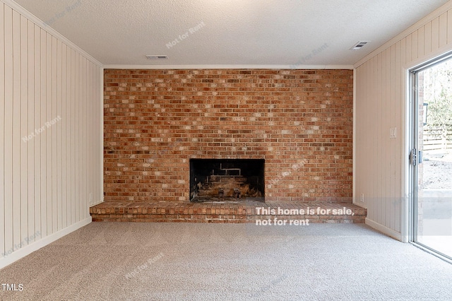 unfurnished living room featuring light colored carpet, a fireplace, brick wall, a textured ceiling, and crown molding