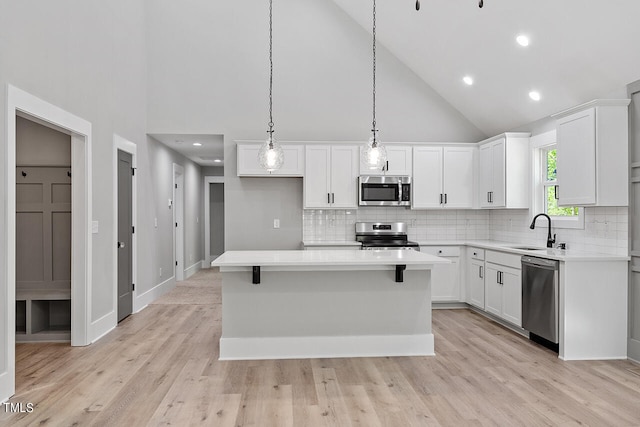 kitchen with sink, stainless steel appliances, white cabinetry, and a center island