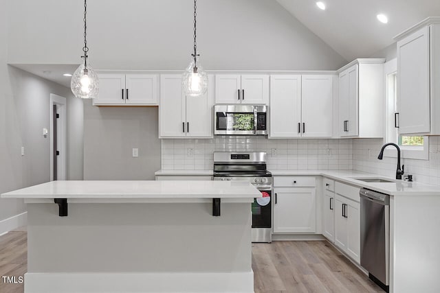 kitchen featuring appliances with stainless steel finishes, hanging light fixtures, a kitchen island, and sink